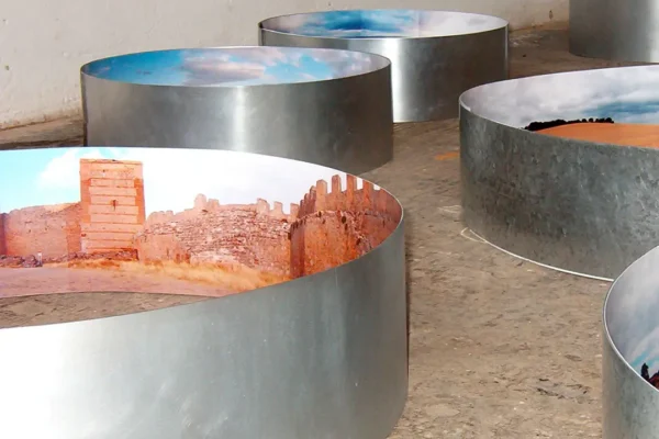 Seis anillos de zinc de distintos diámetros repartidos por el suelo del taller; el mayor muestra en su cara interior una fortaleza de ladrillo rojo con torre cuadrada y almenas.