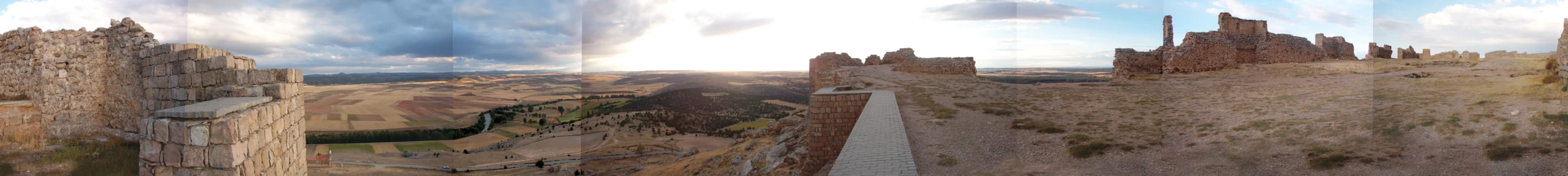 Panorámica de 360° desde el interior de una fortaleza en ruinas: sillares de piedra en primer término y, al fondo, el valle cultivado y más lienzos de muralla derruidos.